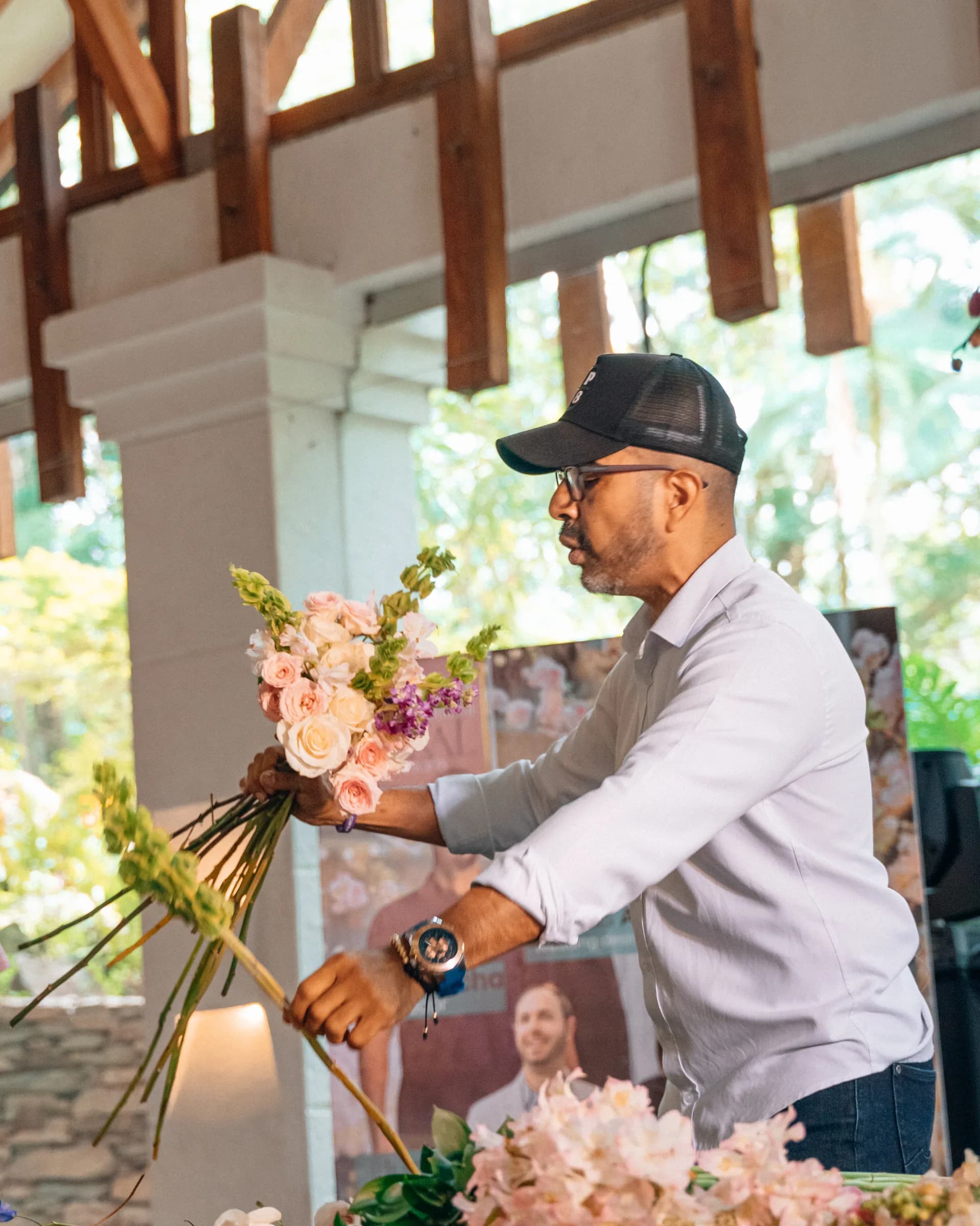 Tomás Acosta arranging a bridal bouquet of pale roses during a floral design workshop